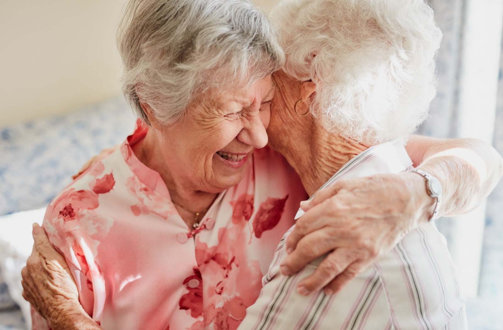Two senior friends share an embrace in a senior living community.